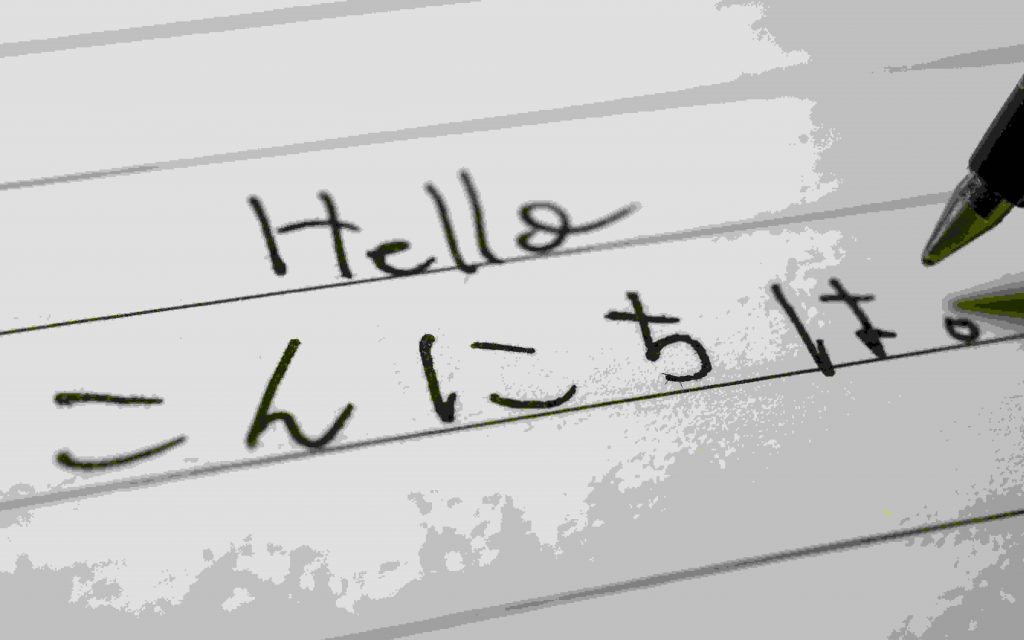 Beginner Japanese language learner writing Hello word in Japanese hiragana characters on a notebook